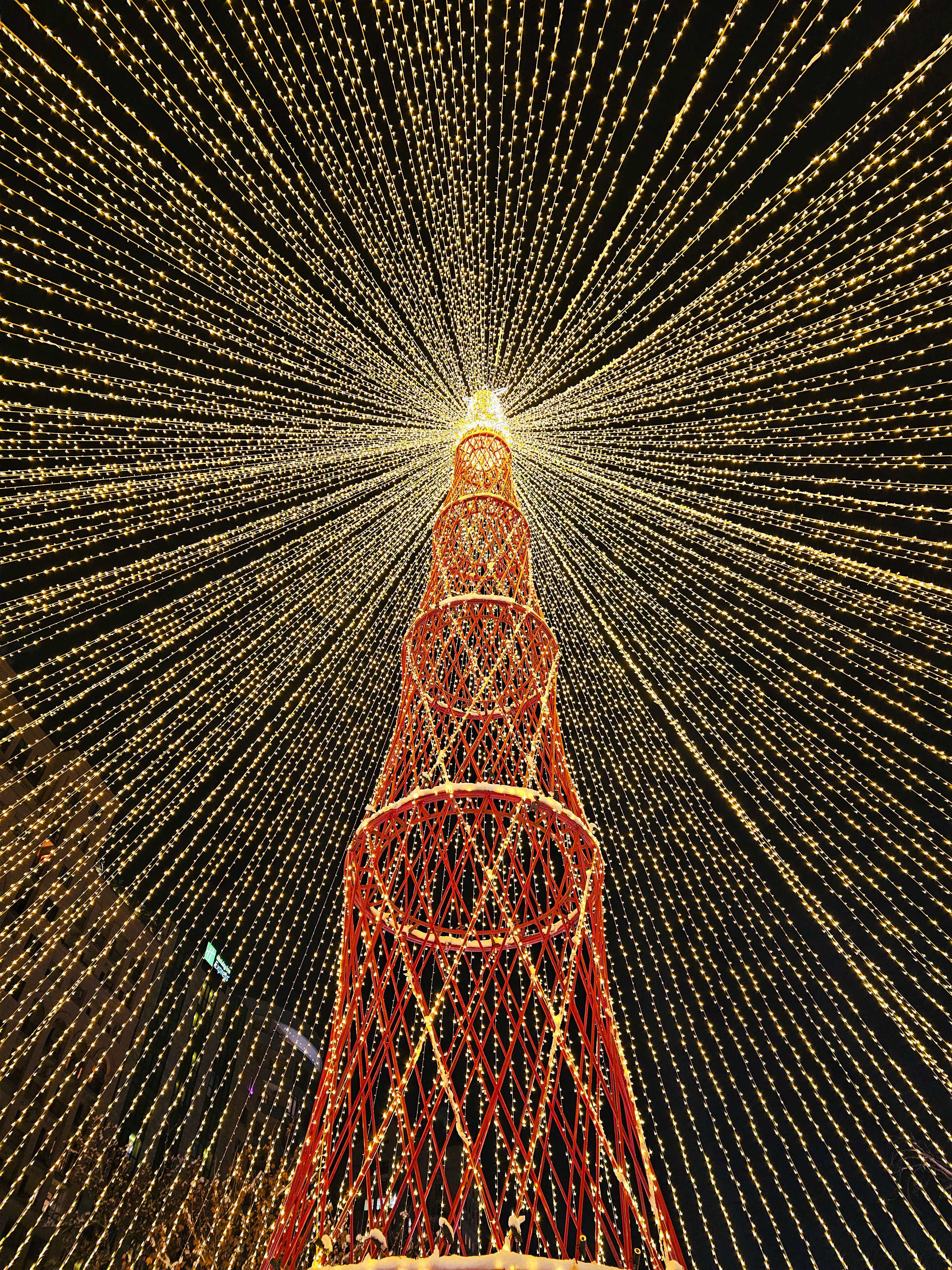 Breathtaking view of a towering Christmas tree with dazzling light decorations creating a radiant pattern.