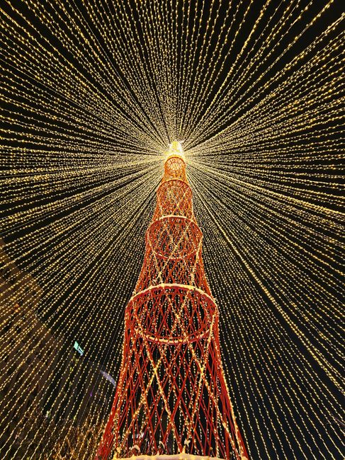 Breathtaking view of a towering Christmas tree with dazzling light decorations creating a radiant pattern.