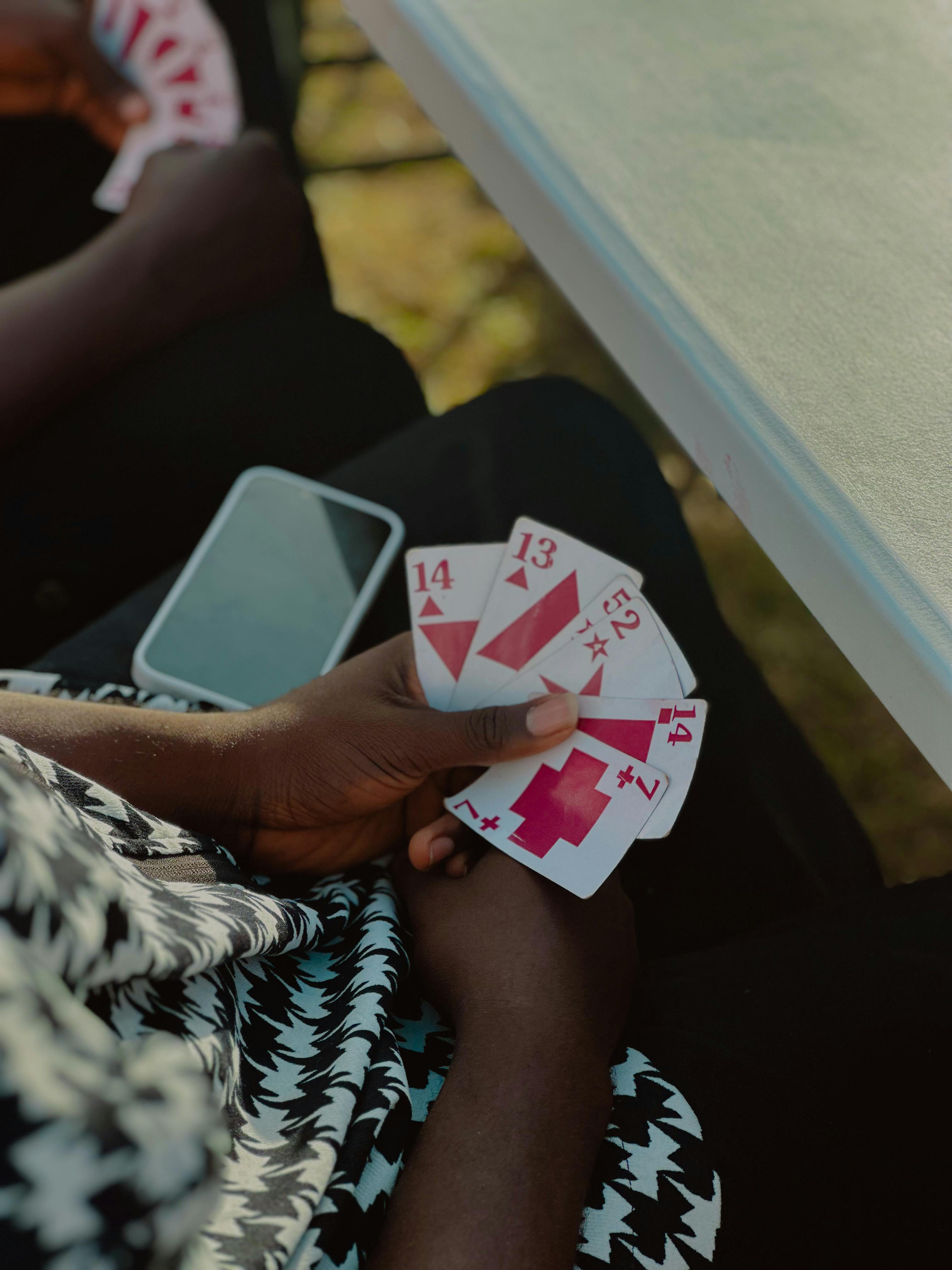 Close-up of hands holding unique playing cards outdoors, capturing a moment of leisure.