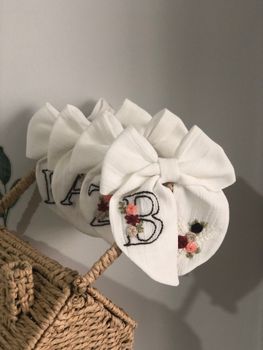 Elegant white hair bows with floral embroidery displayed on a wicker basket. Perfect for fashion shoots.