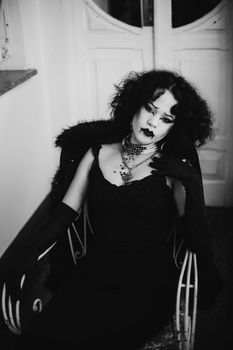 Stylish vintage portrait of a gothic woman with dramatic makeup indoors.