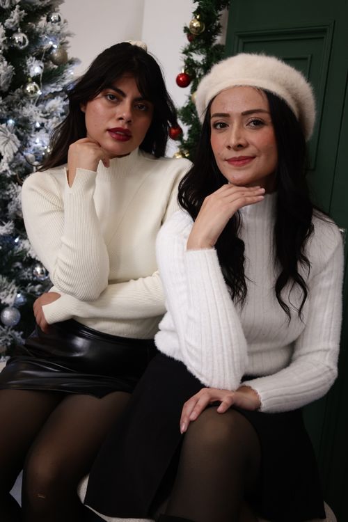 Free Two women in cozy winter outfits pose indoors by a decorated Christmas tree. Stock Photo
