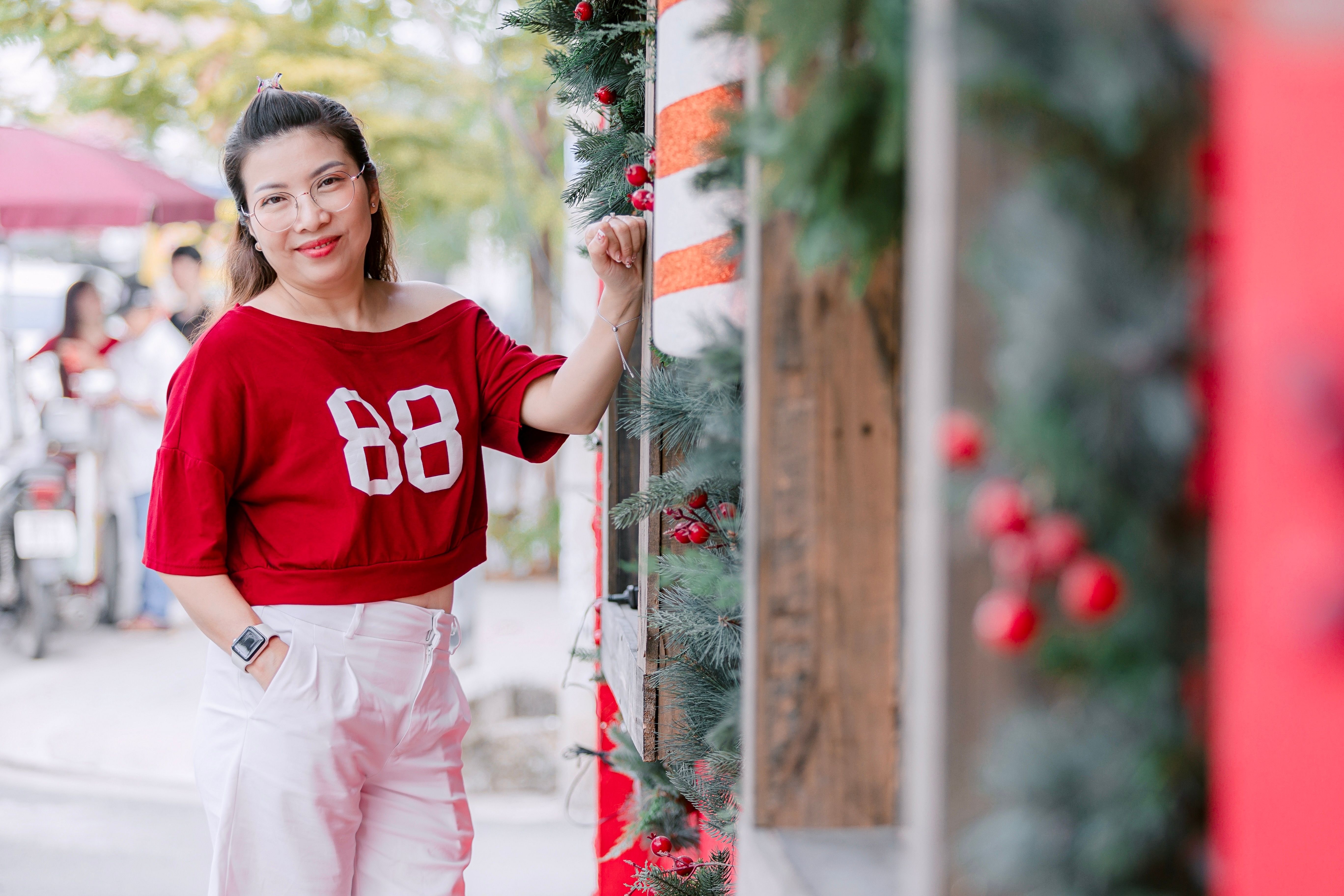 Woman in Red Top Posing Outdoors with Christmas Decor · Free Stock Photo