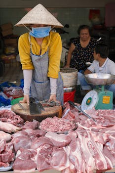 Asian woman selling meat at a traditional wet market in Ho Chi Minh City, Vietnam.