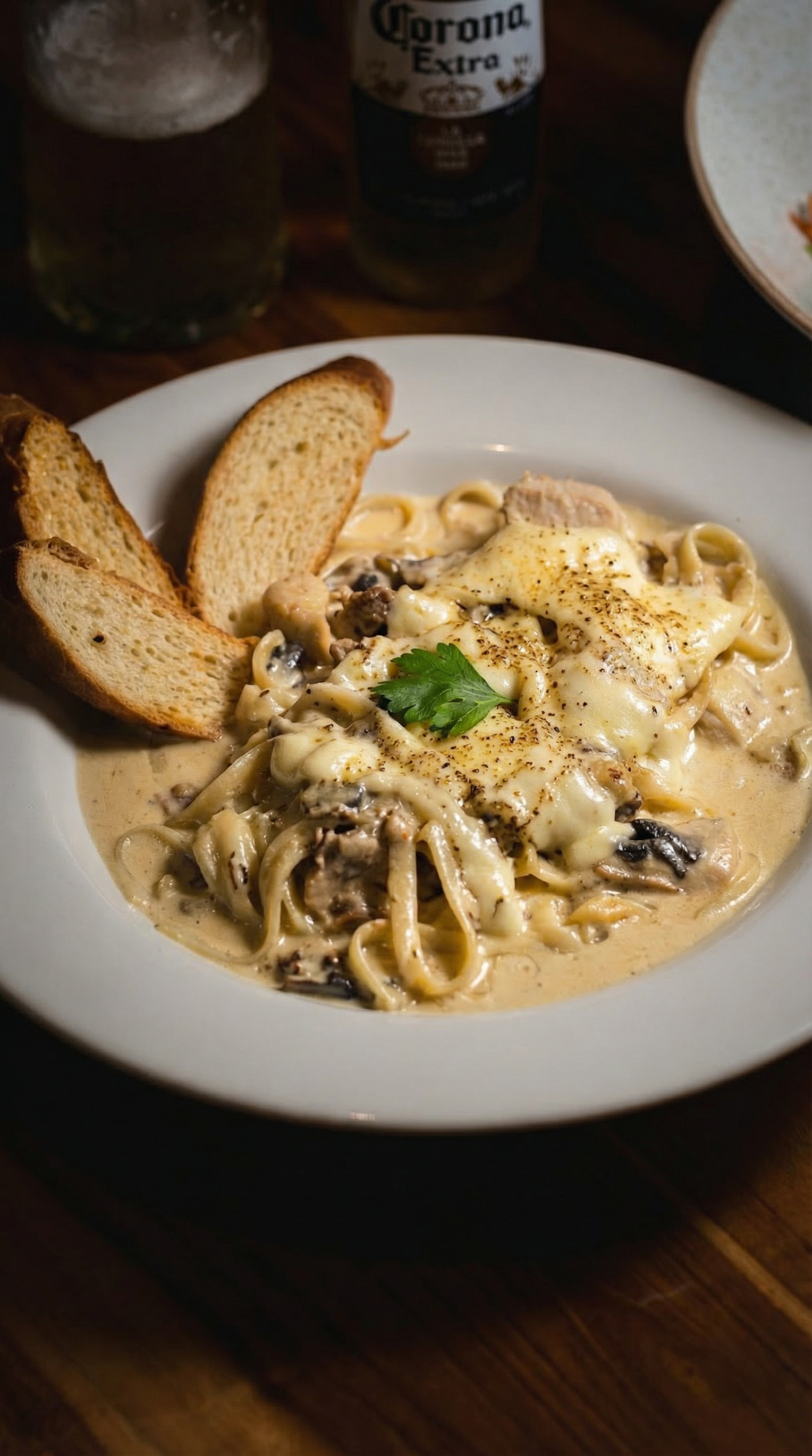 Delicious creamy pasta with bread and beer, perfect for a cozy dining experience in Colombia.