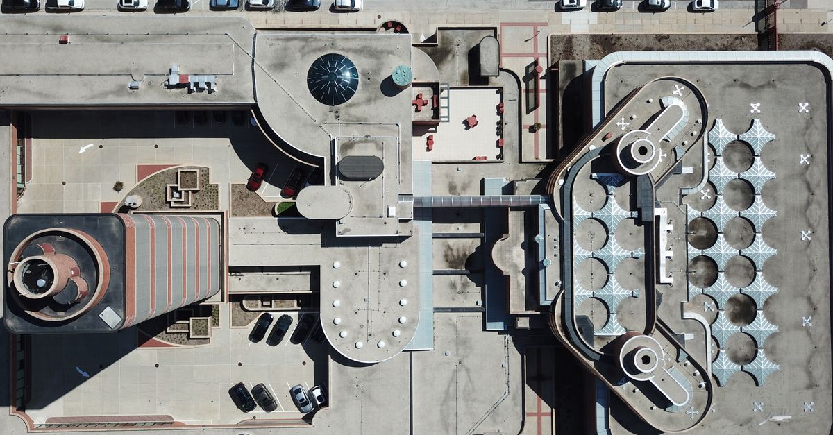Aerial shot of urban architecture with unique rooftop designs and parked cars.