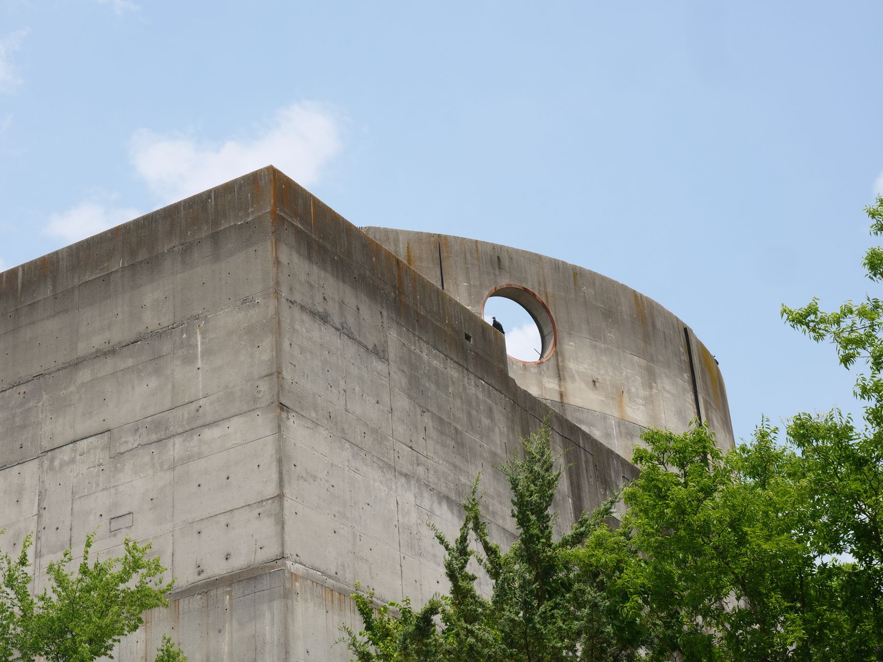 Brutalist architecture showing a concrete building with greenery below and blue sky above.. pexels, brutalist, architecture