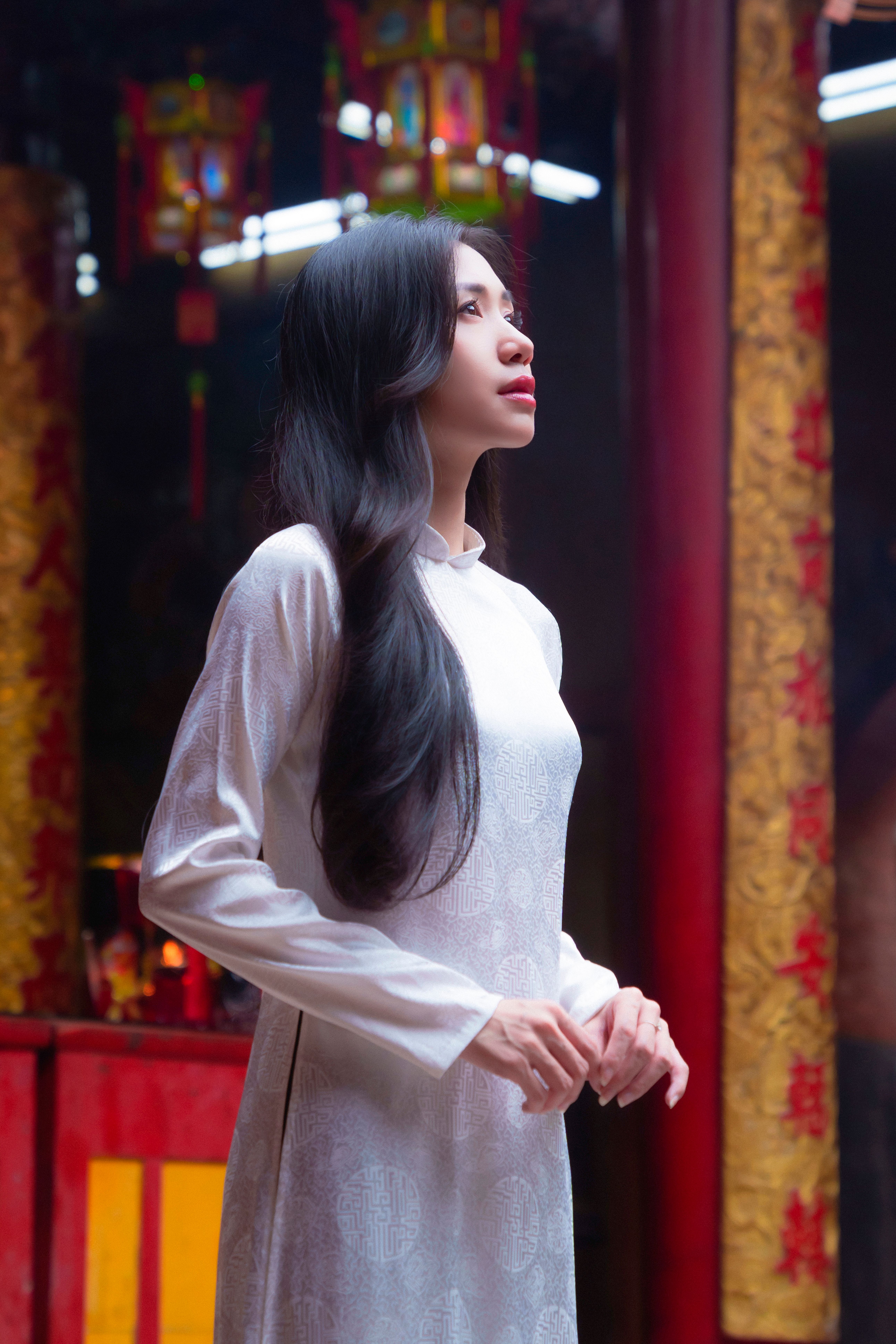 Woman wearing an Ao Dai in a traditional indoor setting.
