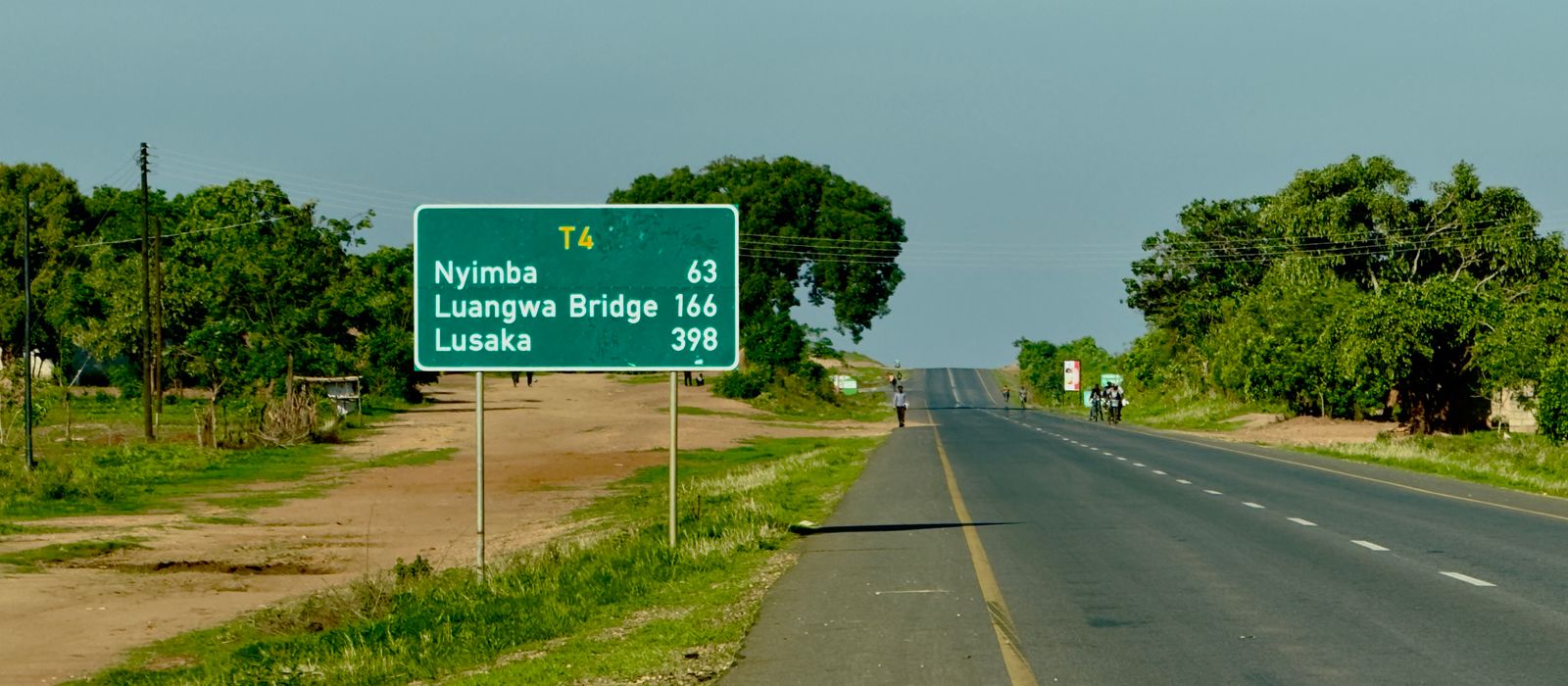 Road sign indicating directions to Nyimba and Lusaka, with a rural landscape. — flights from Entebbe to Lusaka