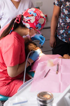A pediatric dentist attends to a child patient in a comfortable clinic setting.