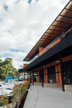 Contemporary commercial building facade with adjacent parking and trees.