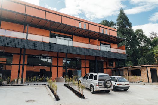 Contemporary brick building exterior with parked cars in an outdoor setting surrounded by greenery.
