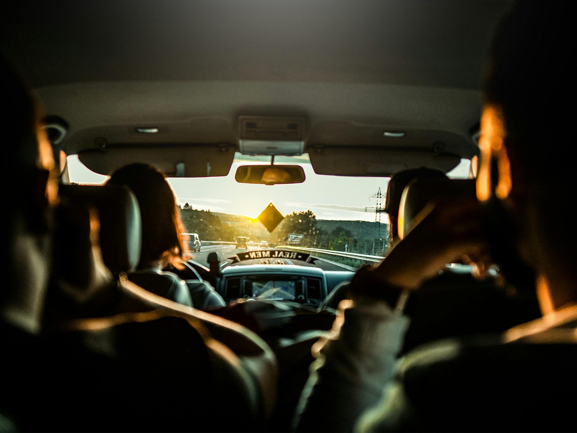 Interior view of a car during a sunset road trip with passengers enjoying the drive.