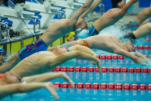 Athletes dive into the pool at a vibrant swimming competition.
