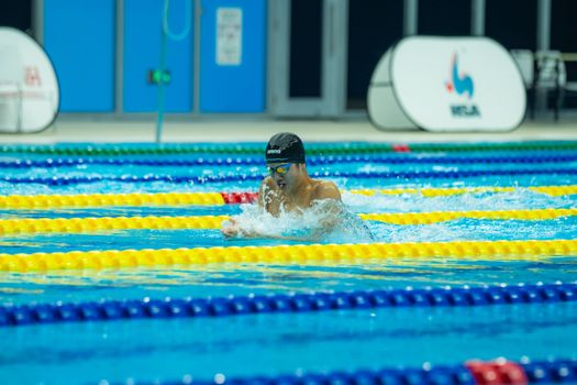 Swimmer in action at an indoor pool during a competitive race, focused on victory.