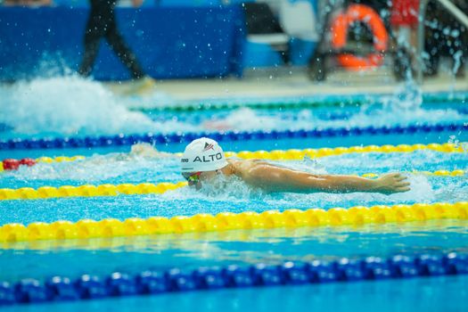 An athlete performs the butterfly stroke during a high-energy swimming competition.