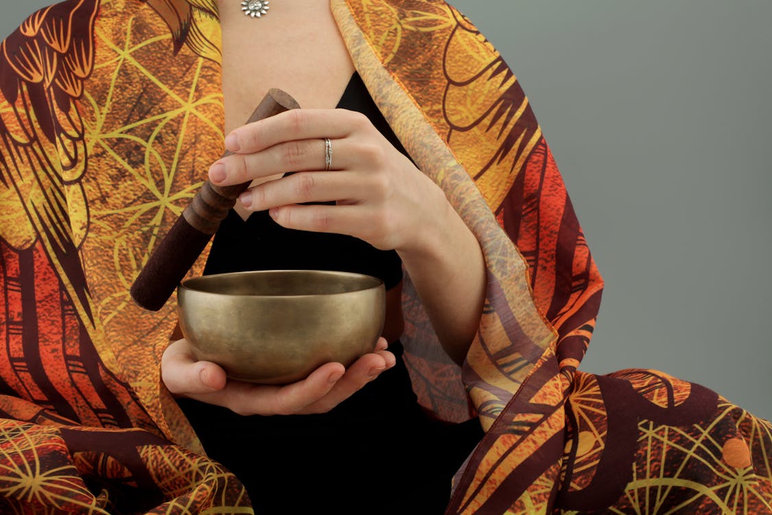 Free Woman Holding a Wooden Stick and a Bronze Bowl Stock Photo