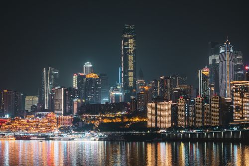 Free A vibrant view of Chongqing's illuminated skyline reflecting on the water at night. Stock Photo