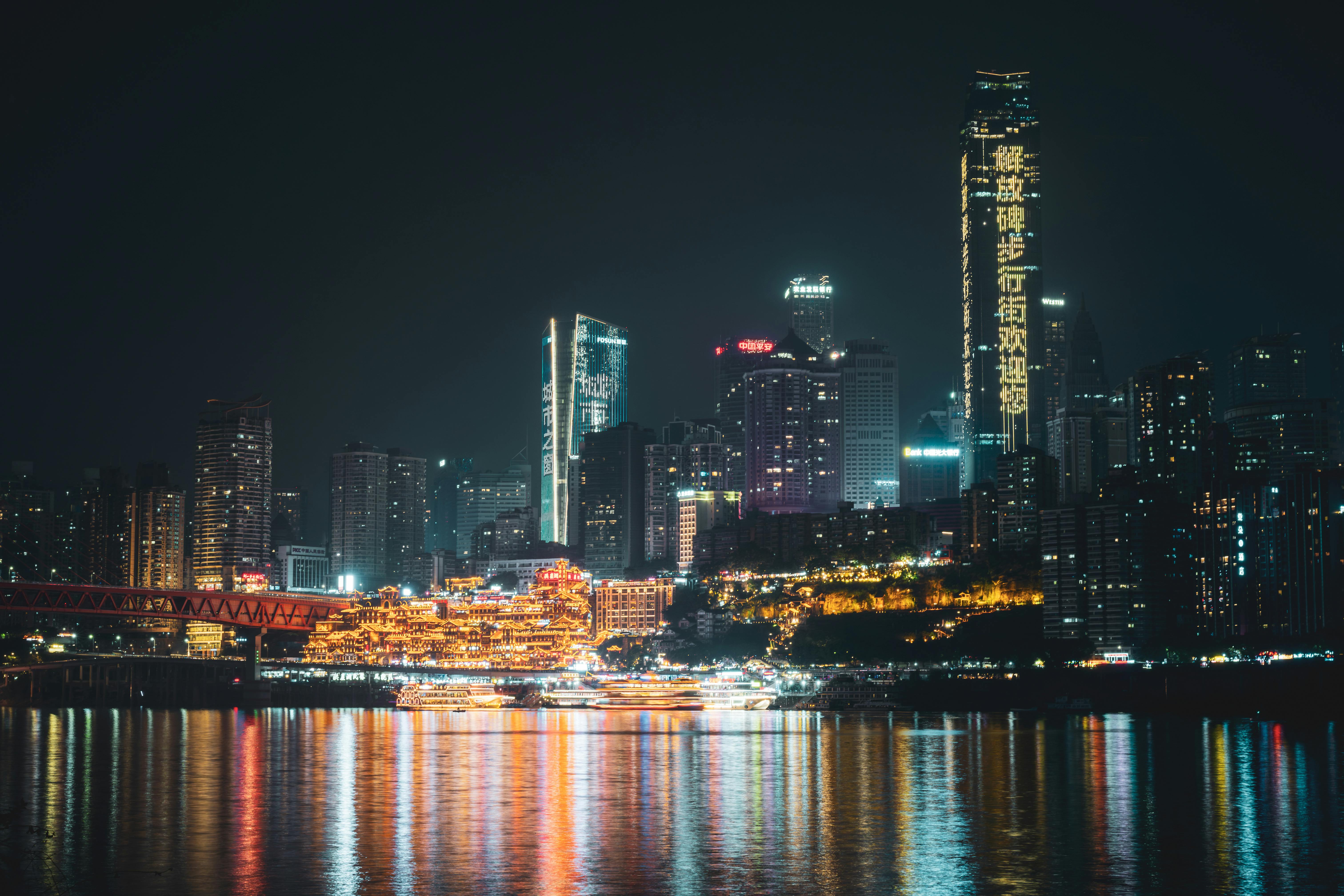 Vibrant Chongqing skyline at night with city lights reflecting in Yangtze River.