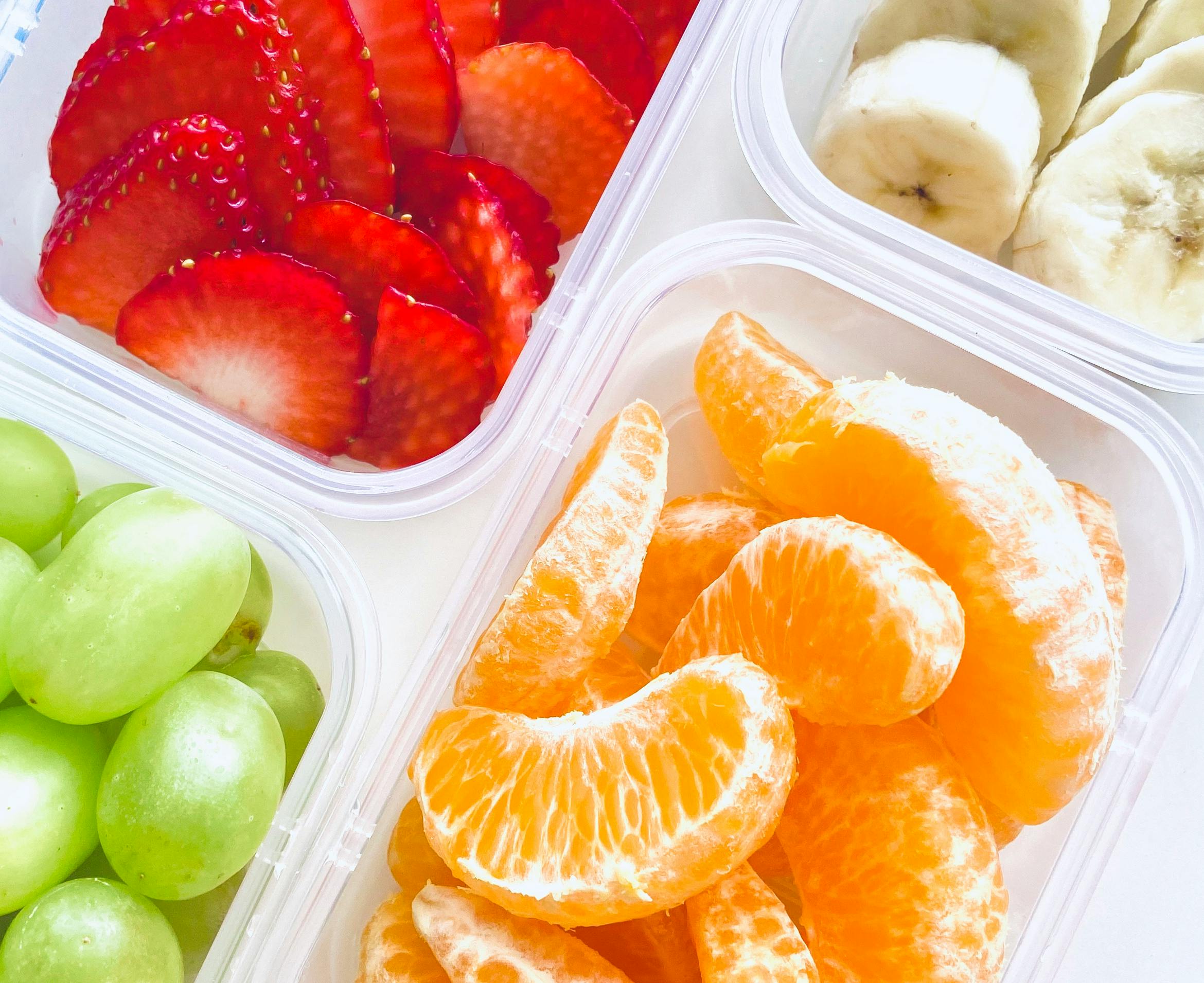 A vibrant and colorful assortment of fresh fruits in clear boxes, perfect for healthy snacking.