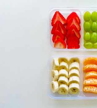 Bright and healthy fruit snack boxes with strawberries, bananas, grapes, and orange slices.