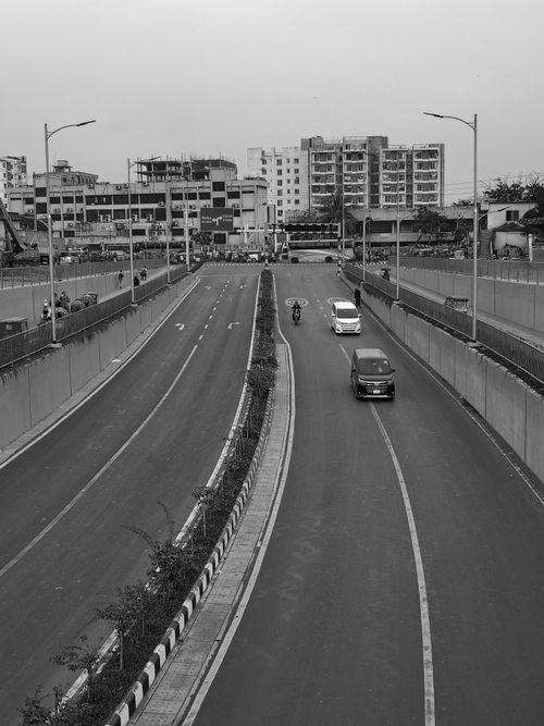 Free Monochrome image of a city underpass with vehicles and buildings, illustrating urban infrastructure. Stock Photo