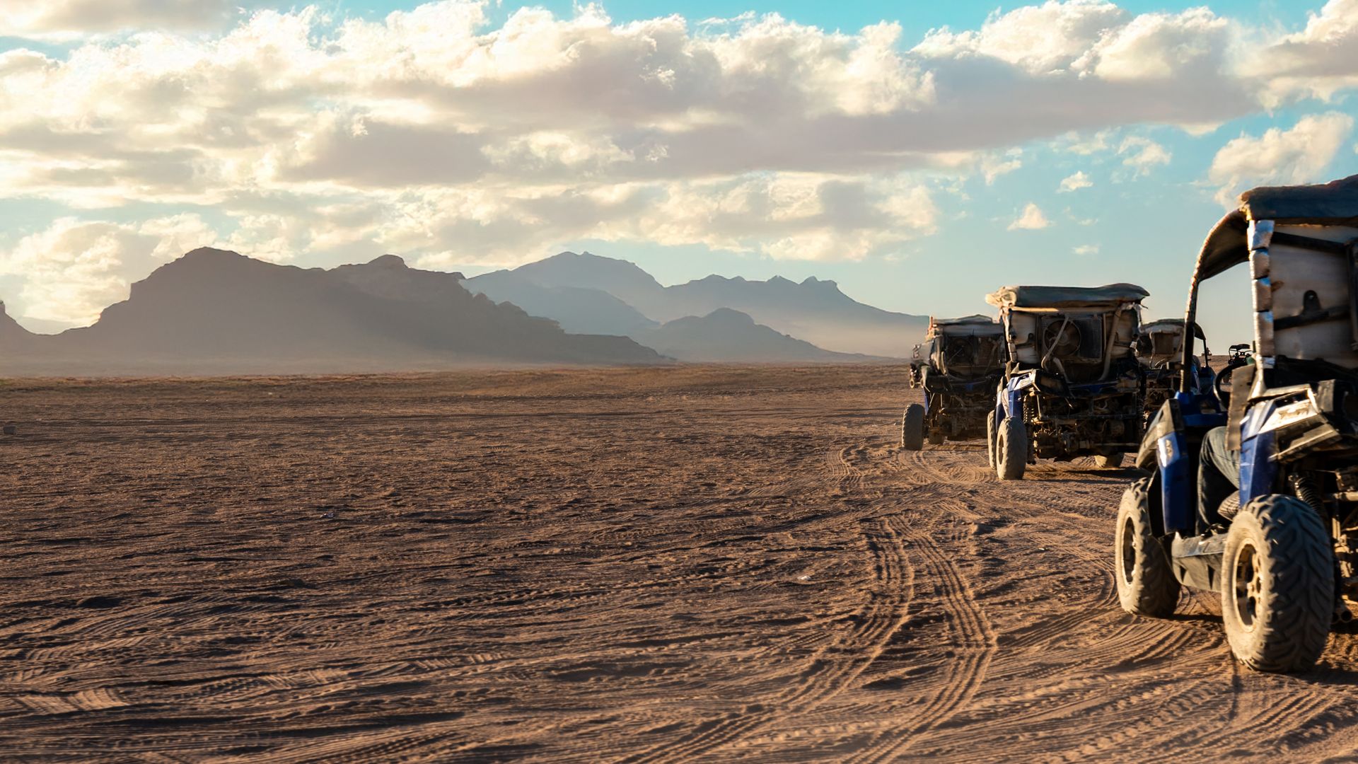 Un convoy militar avanzando por un camino polvoriento al atardecer