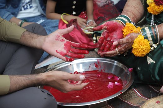 Close-up of hands stained with red dye during a traditional Indian wedding ceremony.