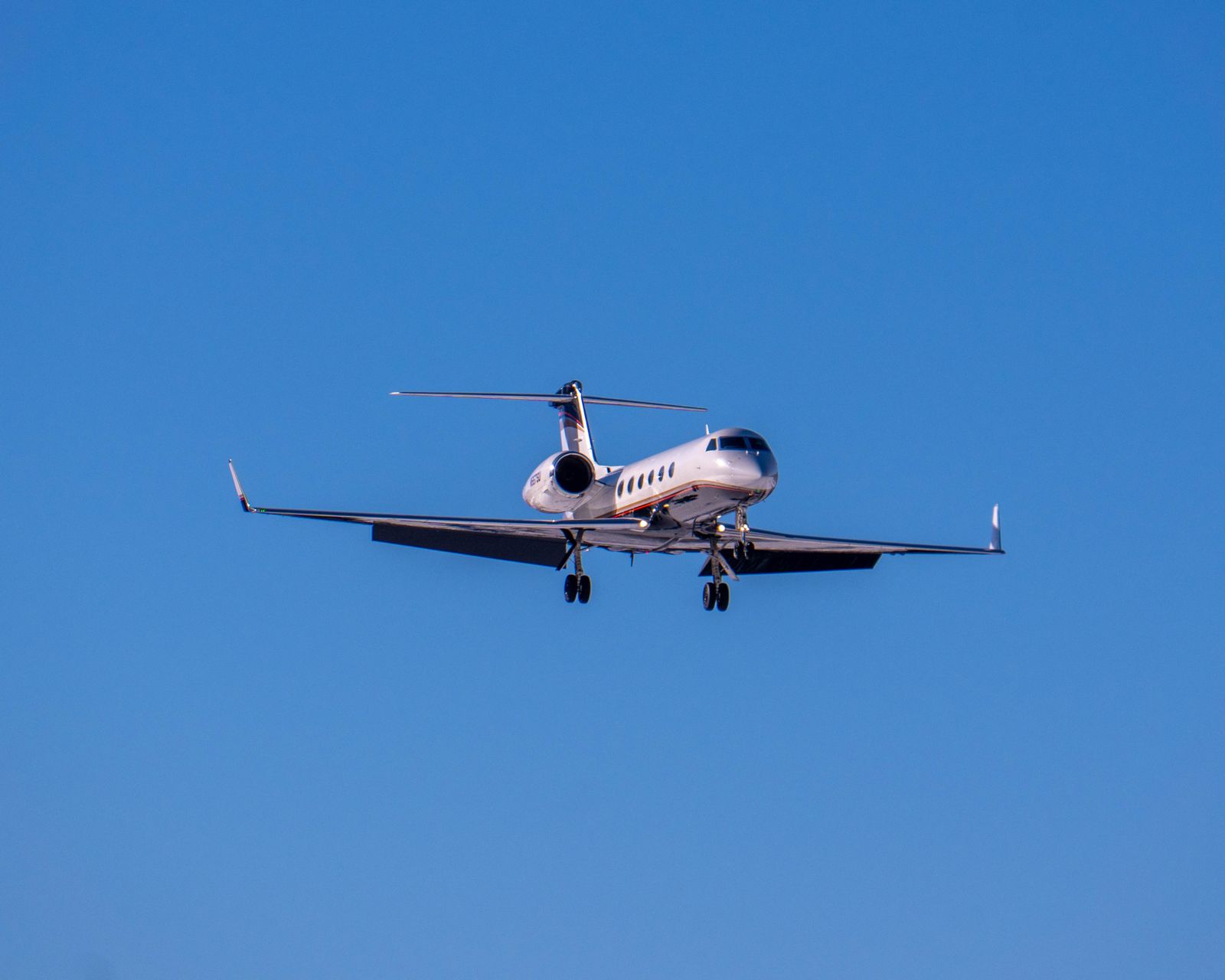 A private jet flying against a bright blue sky, captured from below