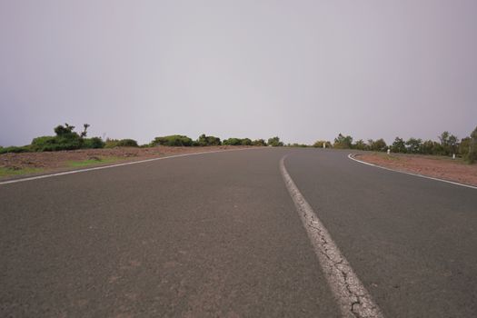 A curving road through a misty landscape in Madeira, ideal for travel and adventure themes.