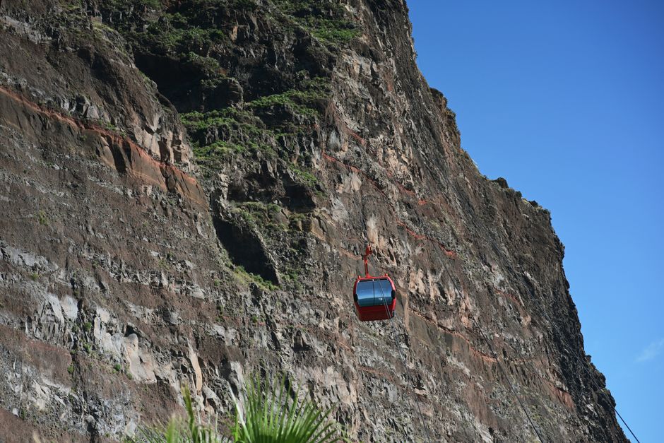 Photo by Ritvars Garoza A bright cable car ascends a rugged cliff on Madeira, Portugal. Adventure awaits.
