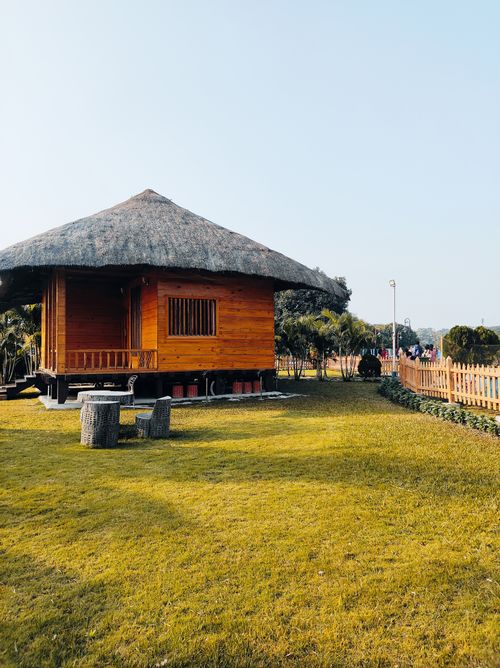Free A charming wooden hut with a thatched roof in a sunny outdoor garden. Stock Photo