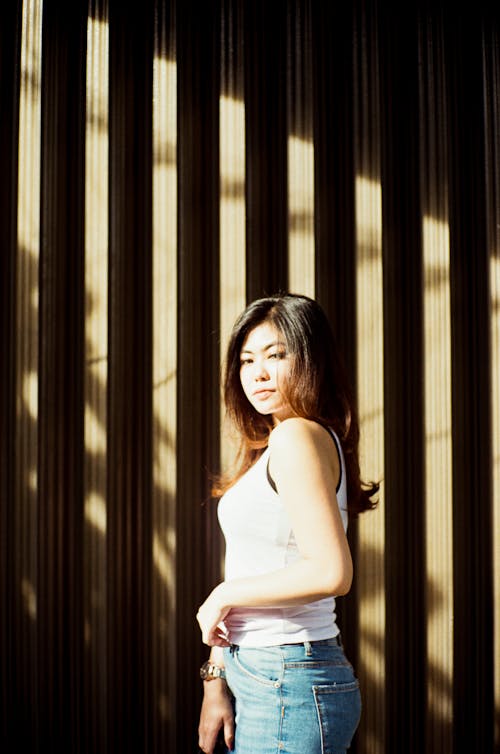 Young ethnic woman in casual outfit standing near wall