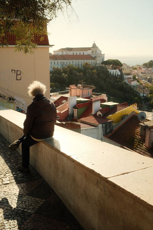 Free A senior person enjoys a sunny day overlooking Lisbon's historic Alfama district. Stock Photo
