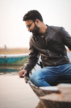 一名男子穿着休闲装，坐在河边的船上，享受着平静的时刻