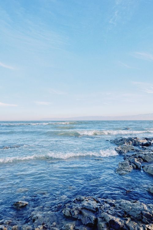 Free A serene view of the rocky shoreline and tranquil sea at Konaev, Kazakhstan under a clear blue sky. Stock Photo