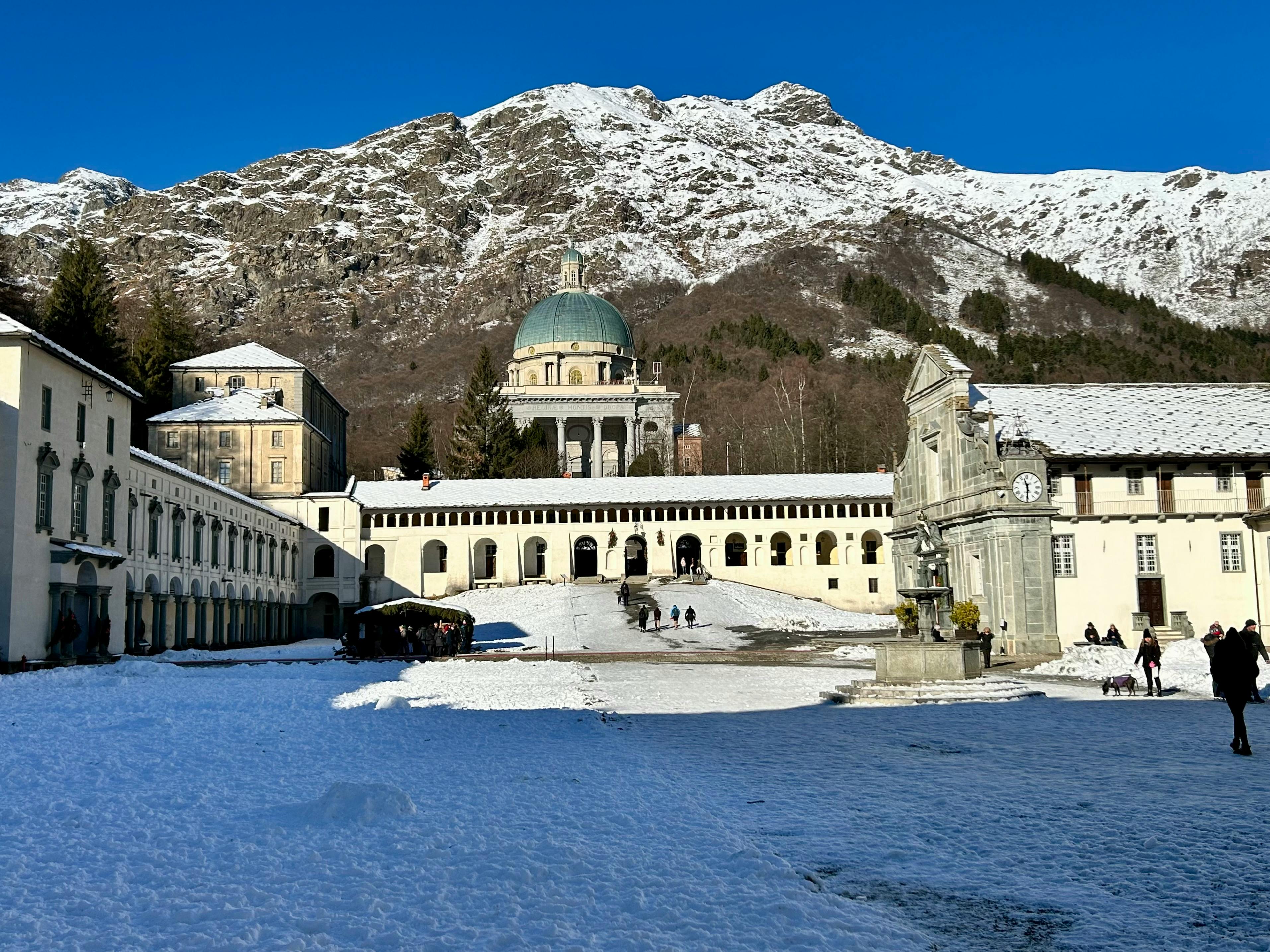 A serene winter scene capturing the Oropa Sanctuary under a clear blue sky in Piemonte, Italy.