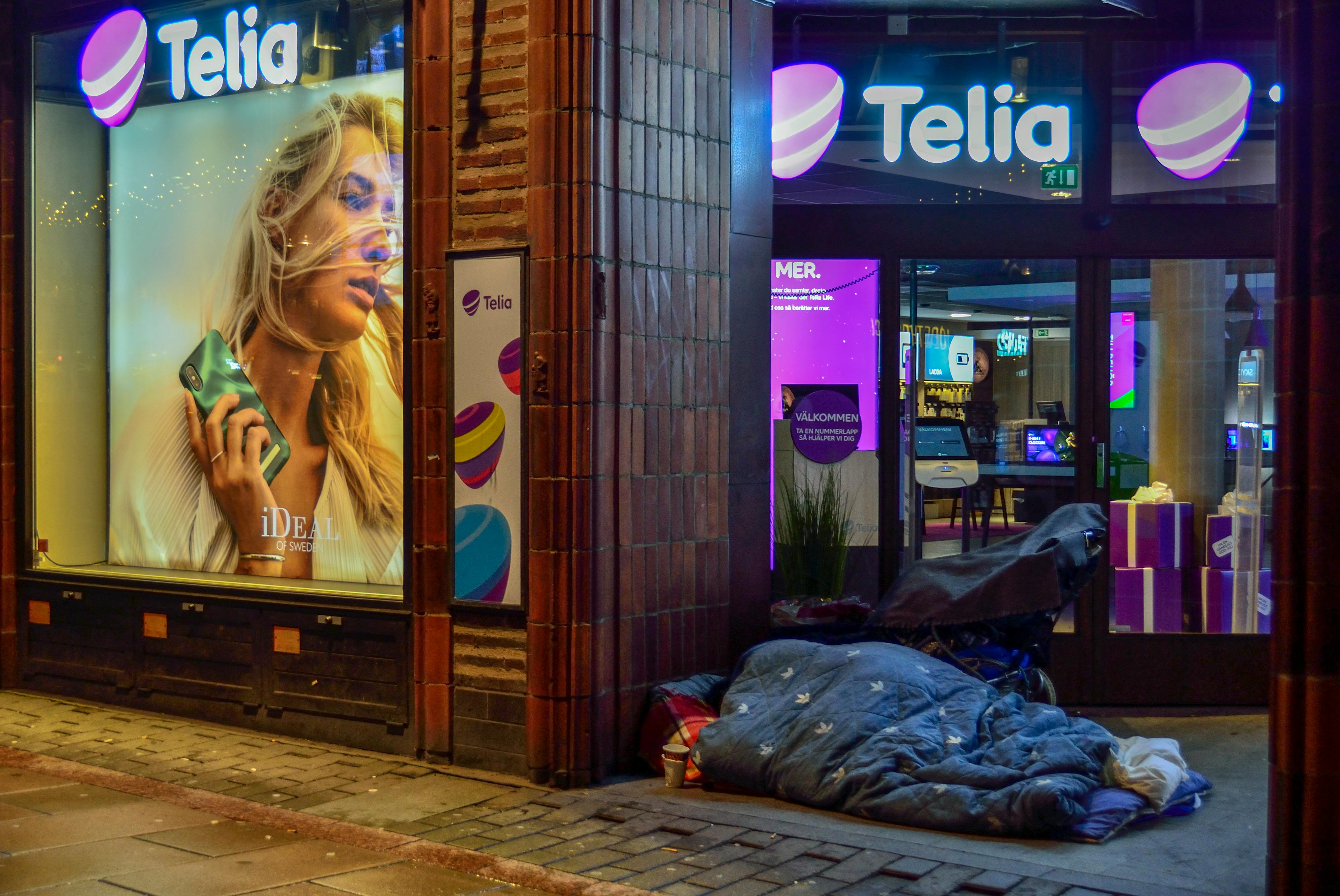 person sleeping in pavement near glass window