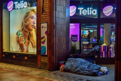 Free A cozy street scene in Stockholm featuring a Telia store with vibrant neon lights during winter night. Stock Photo