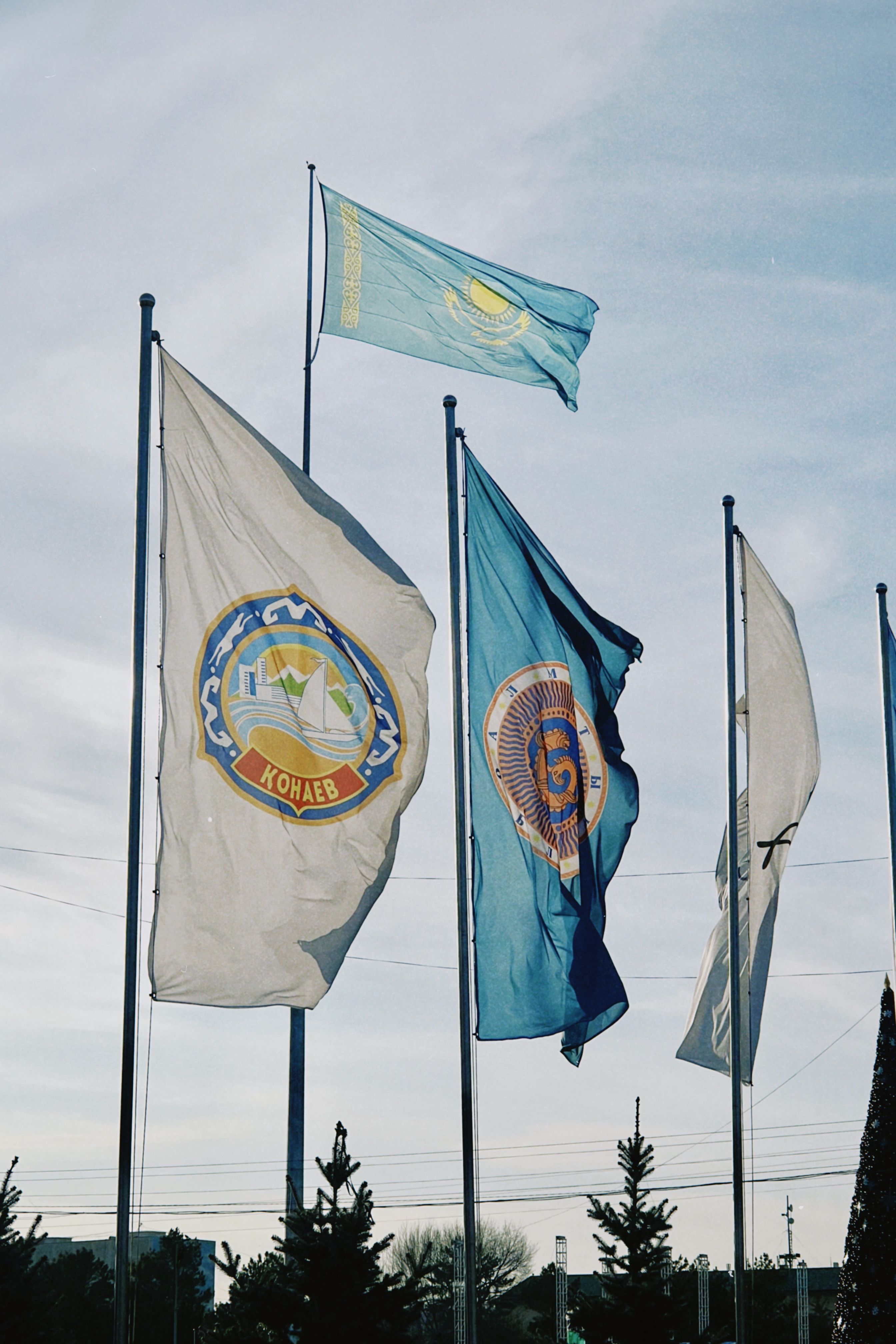Flags waving in the wind in Konaev, Almaty Region, Kazakhstan, under clear skies.