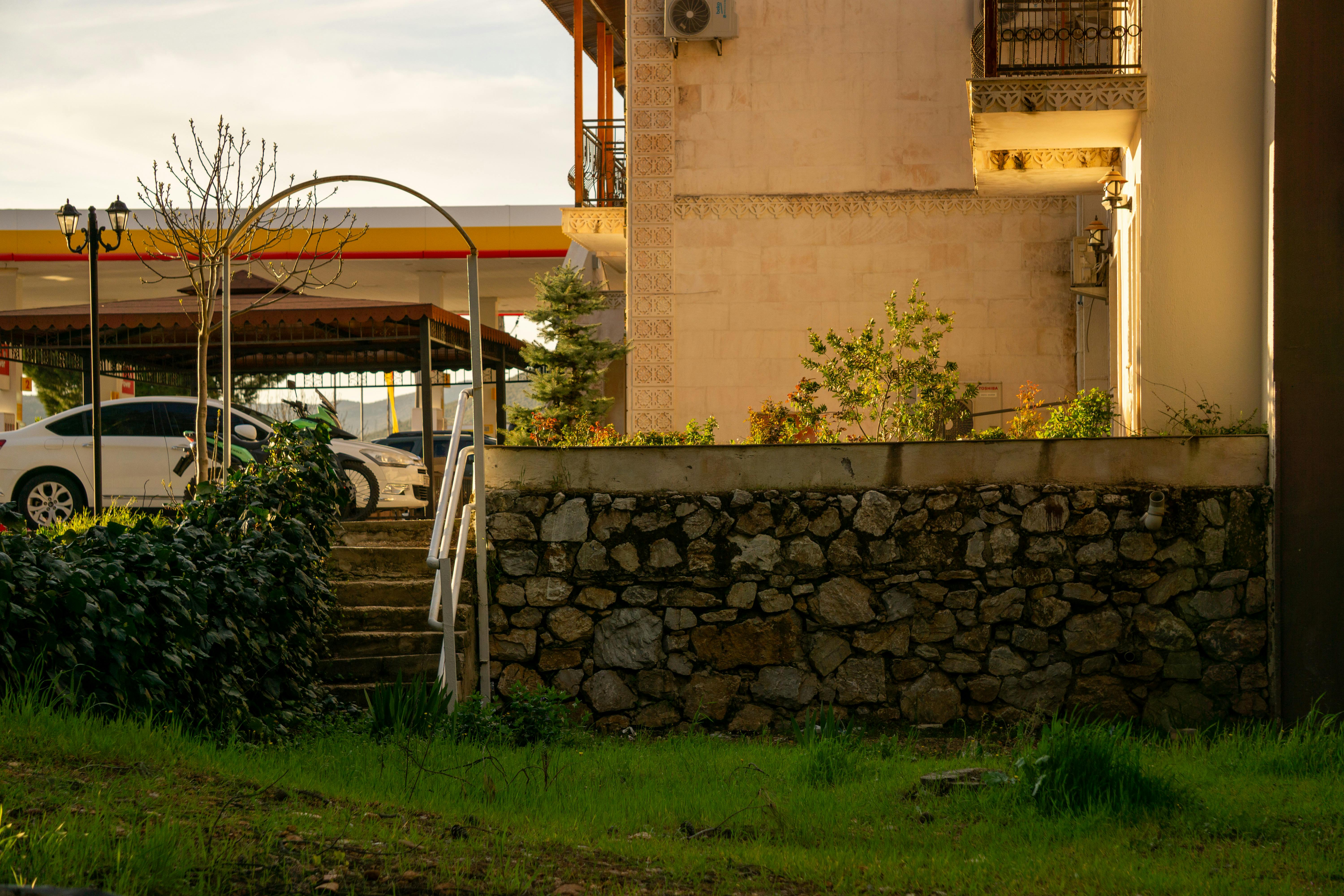 Charming suburban scene with stone wall and nearby gas station under soft lighting.
