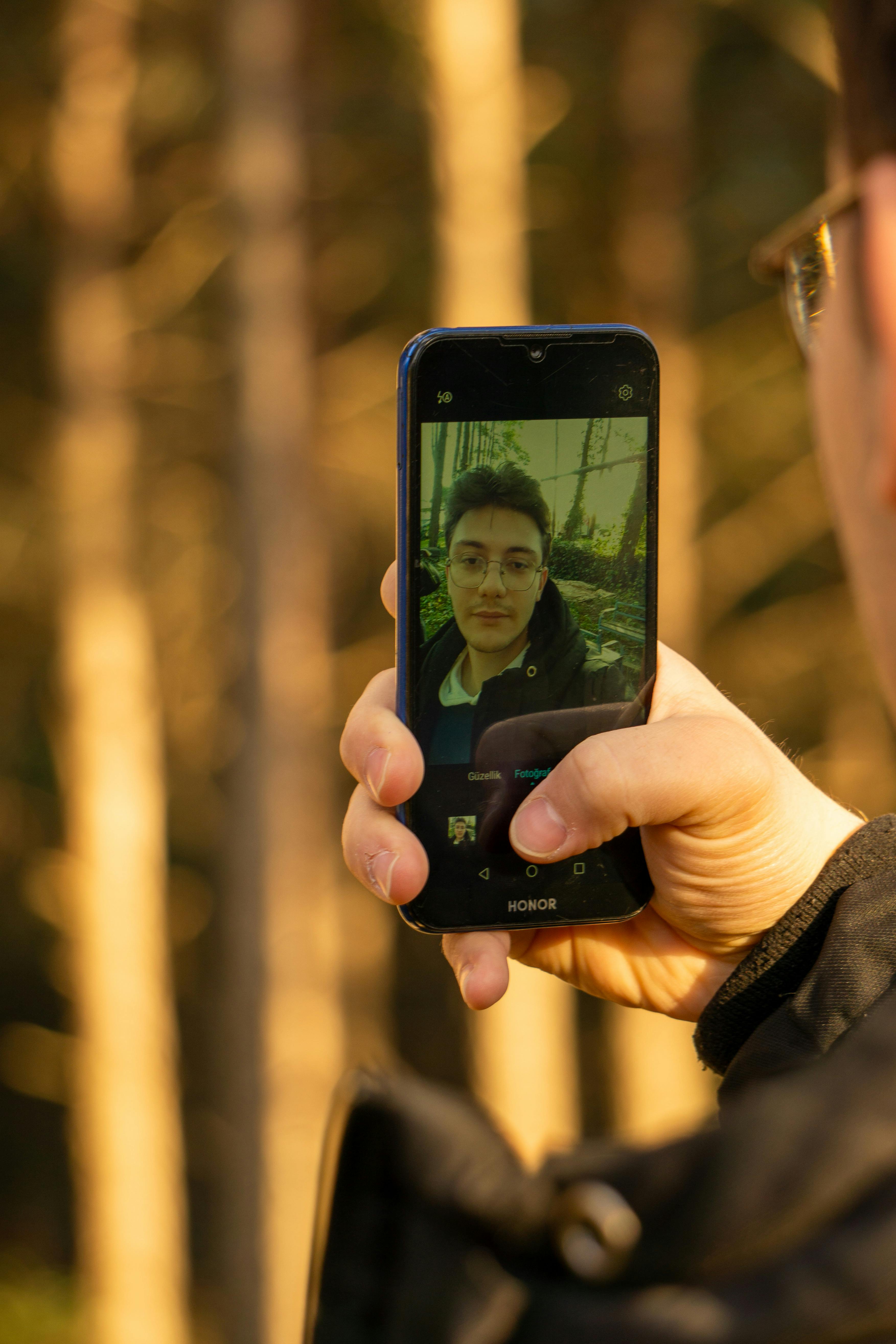 Gratis Primo piano di una persona che si scatta un selfie con uno smartphone all'aperto. Foto a disposizione