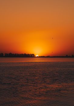 A serene sunset view over the still waters of a lagoon with vibrant orange hues.