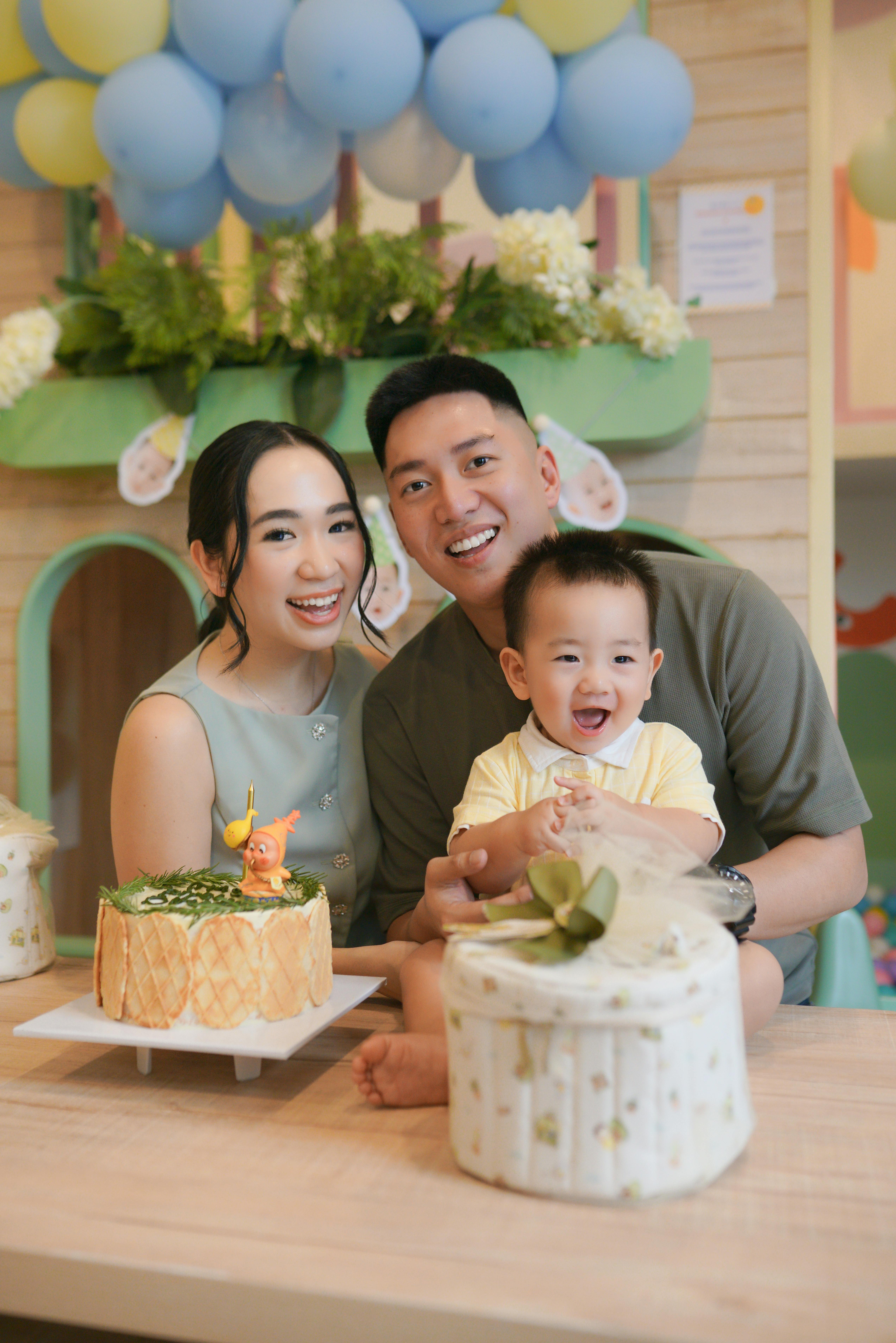 Smiling family enjoying a lively birthday party with decorations and cake.