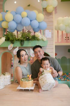 A joyful family celebrates a baby's birthday with a cake and balloons in a festive indoor setting.