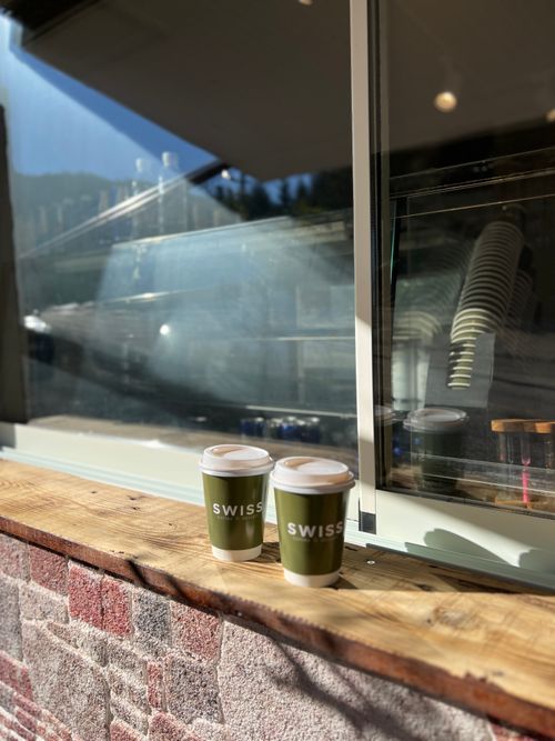 Free Two green Swiss coffee cups on a wooden shelf outside a café window Stock Photo