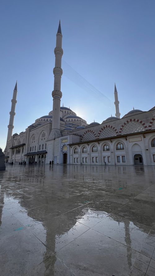 Free Majestic mosque with tall minarets reflecting under clear blue sky. Stock Photo