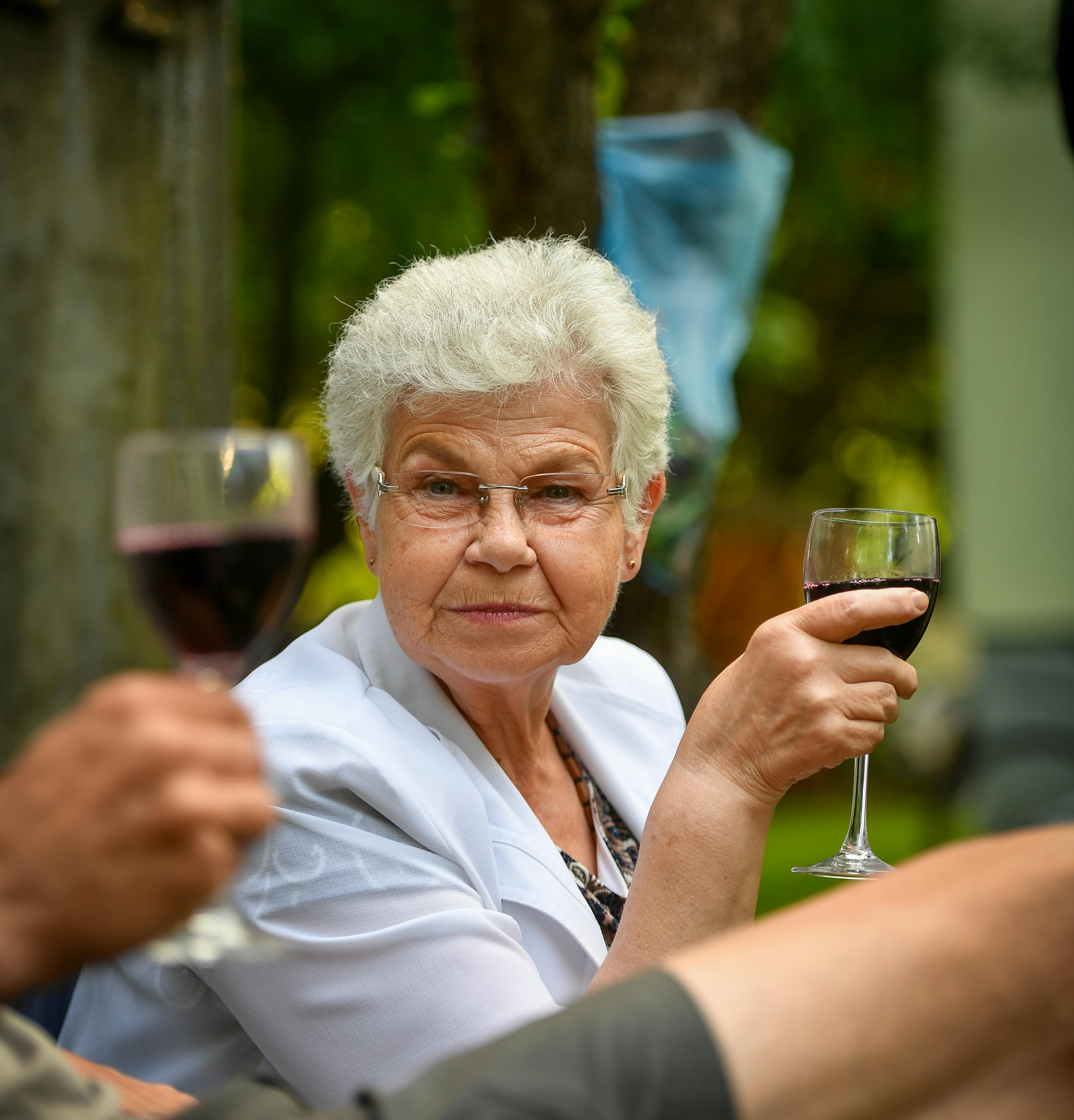 Gratuit Une femme âgée profite d'une joyeuse réunion en plein air avec du vin à Tallinn, en Estonie. Photos