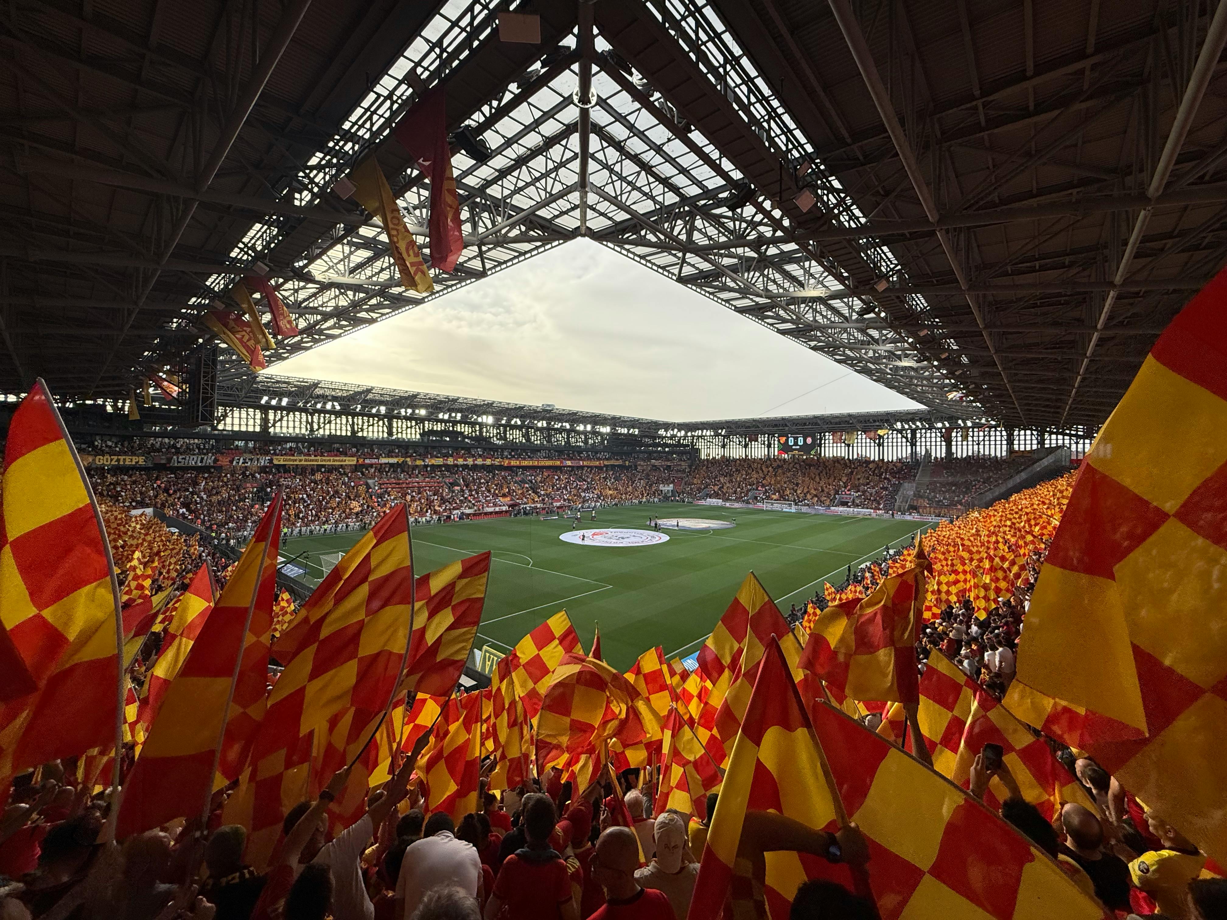 Energetic fans with flags create a lively atmosphere at İzmir football stadium.