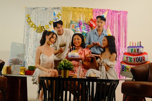 Group of friends celebrating a birthday indoors with cake and decorations.